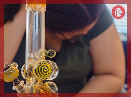 a woman uses a bong to get high on marijuana wax