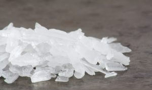 Crystal meth in its glass-like form, appearing shiny and as whitish crystalline rocks.